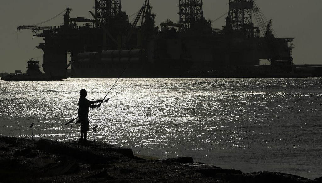 A man fishes near docked oil drilling platforms in Port Aransas, Texas. (AP)