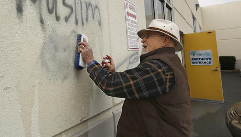 Tom Garing cleans up racist graffiti painted on the side of a mosque in what officials are calling an apparent hate crime, Wednesday, Feb. 1, 2017, in Roseville, Calif. (AP Photo/Rich Pedroncelli)