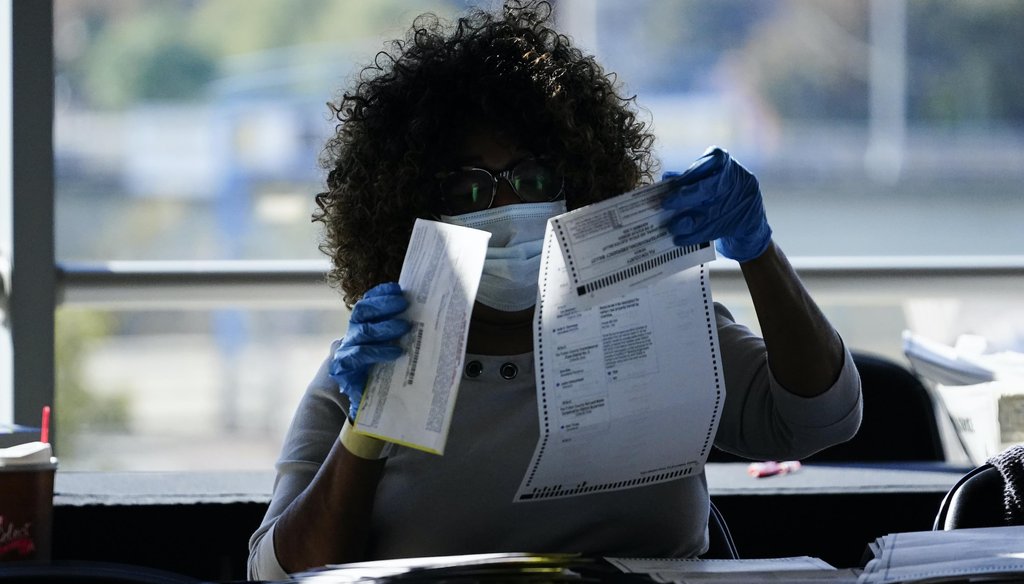 An election personnel examines a ballot as vote counting in the general election continues at State Farm Arena on Nov. 4, 2020, in Atlanta. (AP)