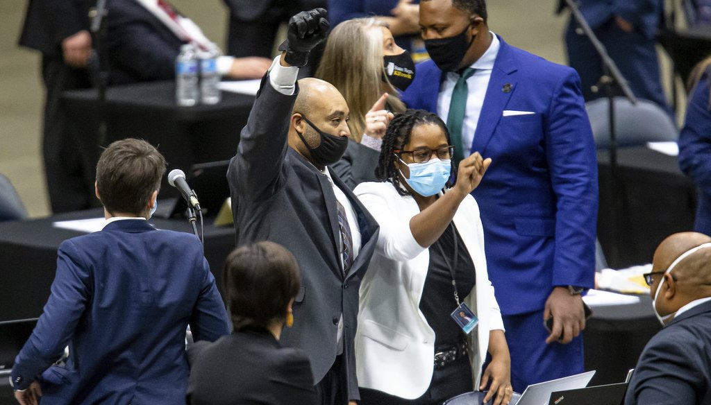 Illinois Rep. Justin Slaughter, D-Chicago, center, holds up his fist while wearing a black glove after a criminal justice reform bill passed the Illinois House of Representatives in Springfield, Ill. (Justin L. Fowler/The State Journal-Register)