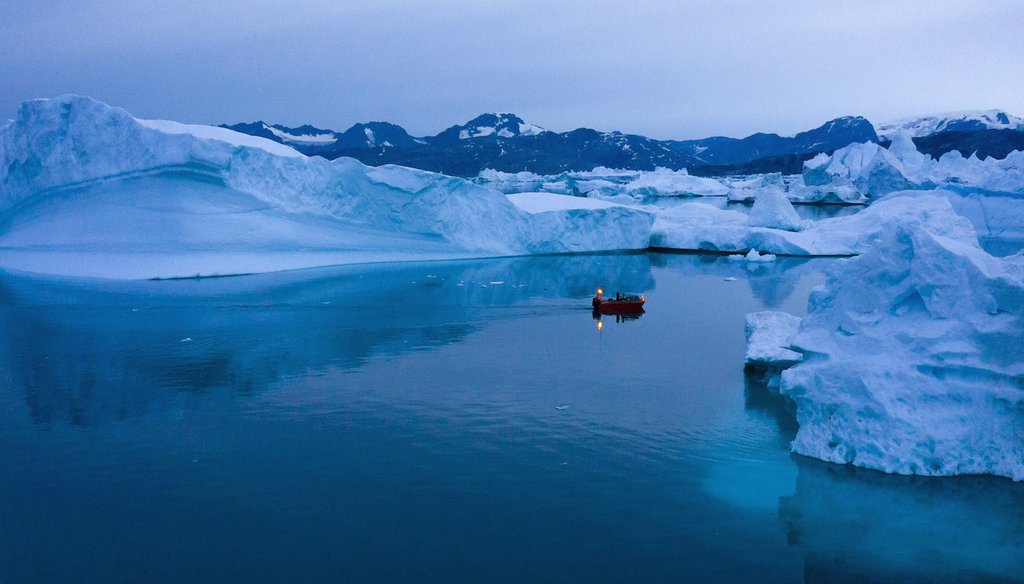 A boat navigates at night between icebergs in eastern Greenland, late Friday, Aug. 15, 2019 (AP).