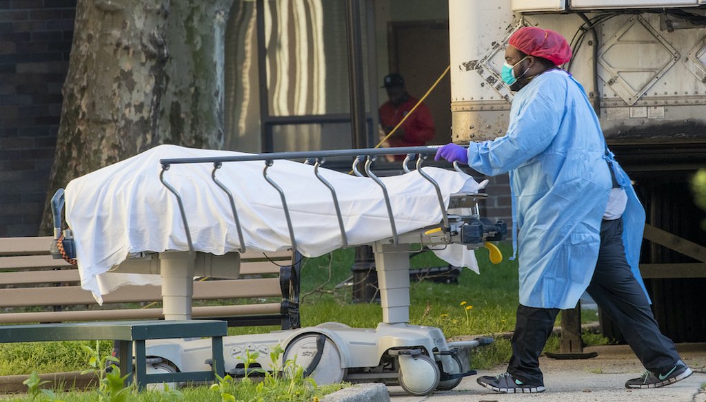 Medical personnel transport a body from a refrigerated container at Kingsbrook Jewish Medical Center. (AP Photo/Mary Altaffer)