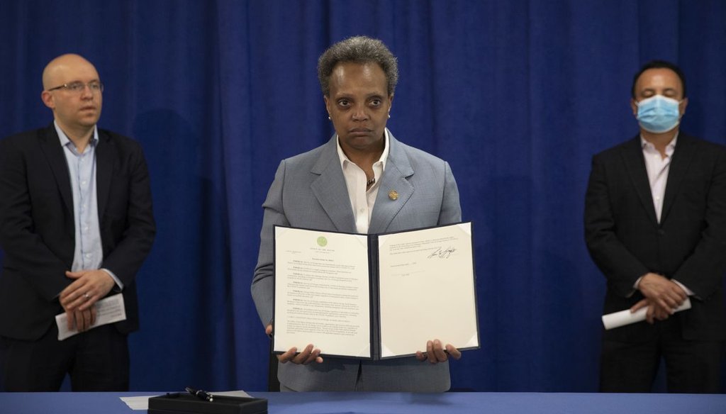 Mayor Lori Lightfoot signs an executive order on April 7, 2020 to ensure coronavirus-related benefits offered by the city of Chicago are available to immigrants and refugees. (Ashlee Rezin Garcia/Sun-Times)