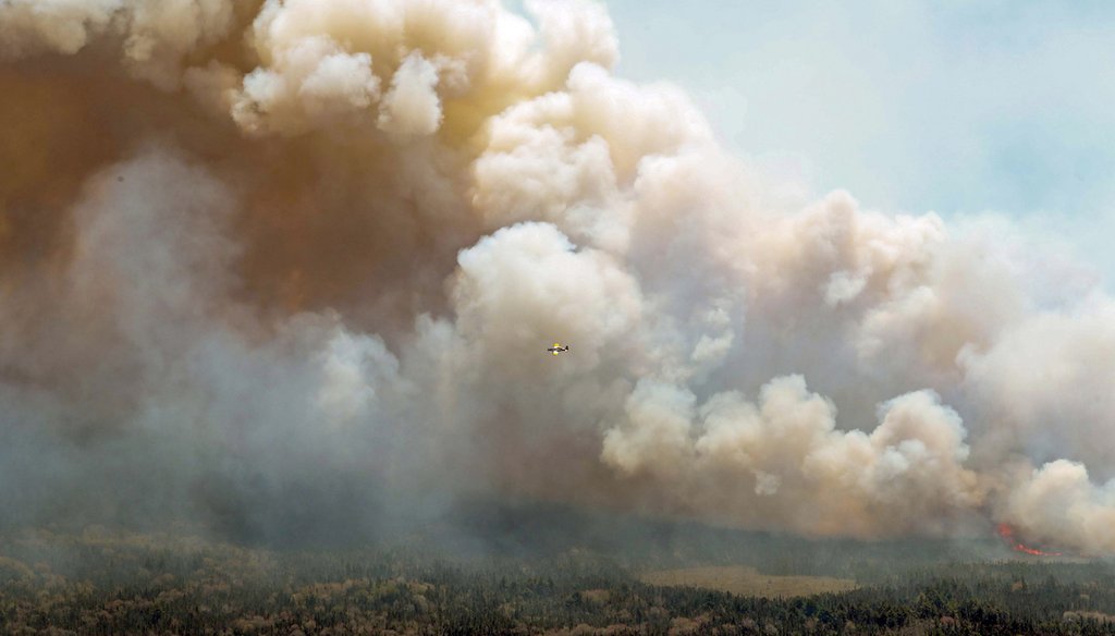 In this aerial image, an aircraft, center, flies near a wildfire burning near Barrington Lake in Shelburne County, Nova Scotia, on Wednesday, May 31, 2023. (AP)