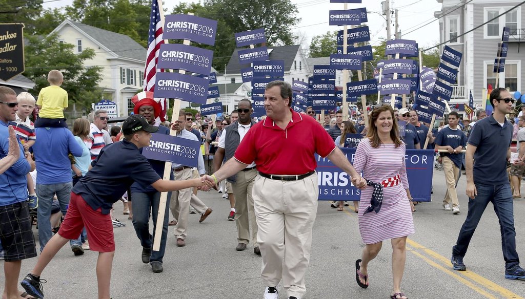 Republican presidential candidate New Jersey Gov. Chris Christie shakes hands as he walks in a Fourth of July parade with his wife wife Mary Pat in Wolfeboro, N.H. (AP Photo)