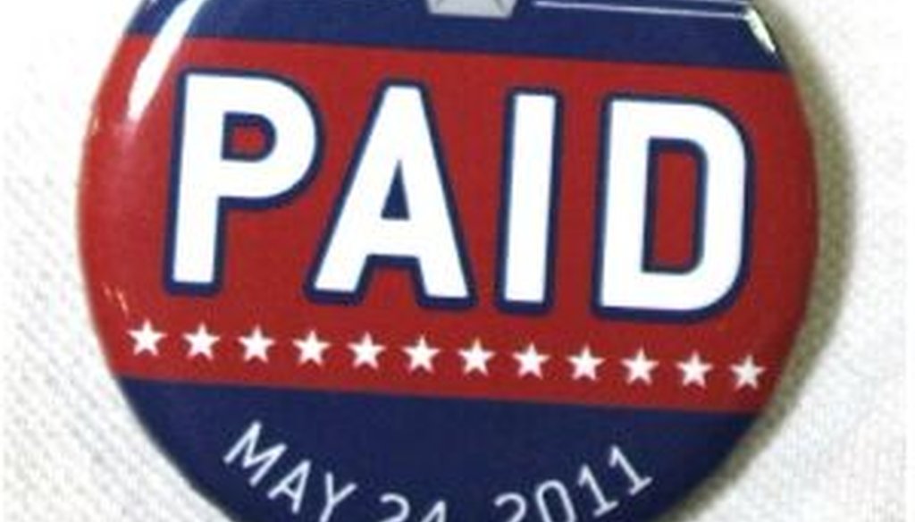 A Chrysler assembly line worker sports a pin labled "PAID" on his shirt before Chrysler Group announced the repayment of the remainder of its loans from the U.S. Government.