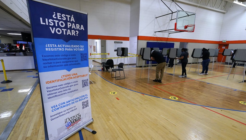 A sign in Spanish stands near voters as they cast their ballots at stations inside the La Familia Recreation Center in the Baker neighborhood Tuesday, Nov. 3, 2020, south of downtown Denver. (AP)