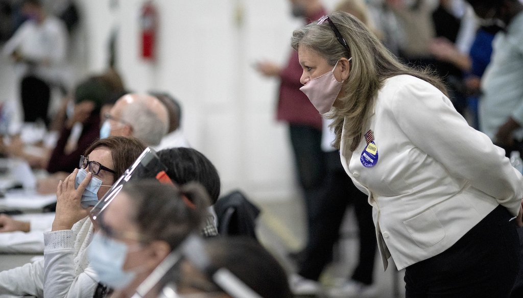 A Republican election challenger at right watches over election inspectors as they examine a ballot as votes are counted into the early morning hours, Nov. 4, 2020, at the central counting board in Detroit. (AP)