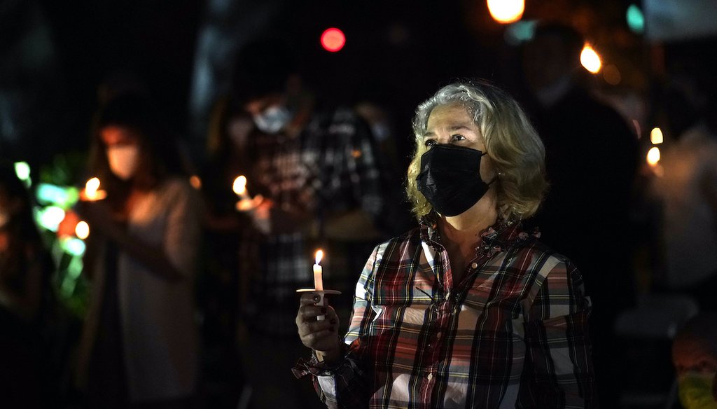 A woman wears a protective face mask while holding a candle during an outdoor Christmas Eve Service of Lights at the Granada Presbyterian Church, Thursday, Dec. 24, 2020, in Coral Gables, Fla. The service was held outdoors for COVID-19 safety. (AP)