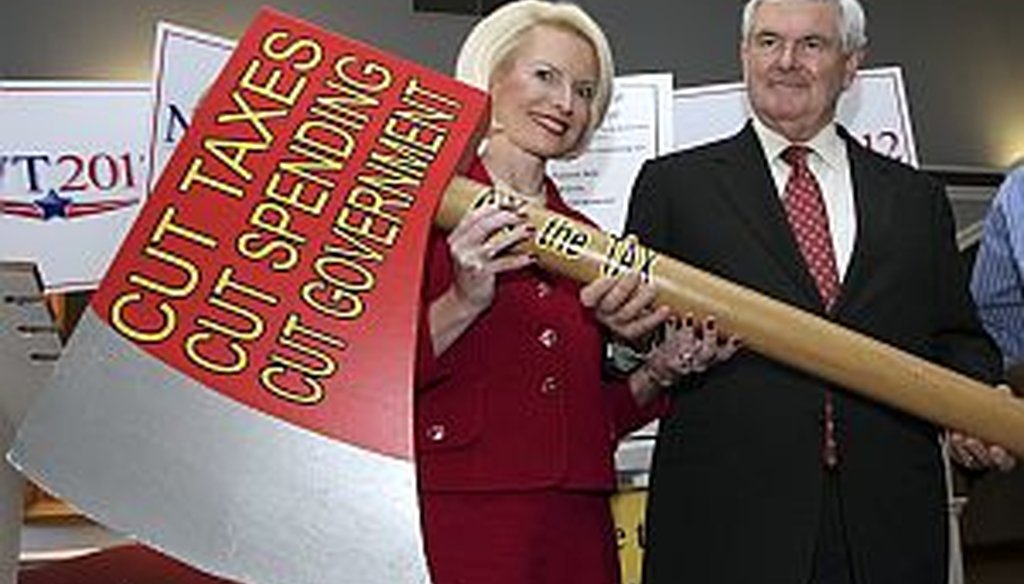 Former House Speaker Newt Gingrich, with his wife Callista, holds an oversize replica of an ax after signing a pledge to cut government Oct. 25 in Concord, N.H.