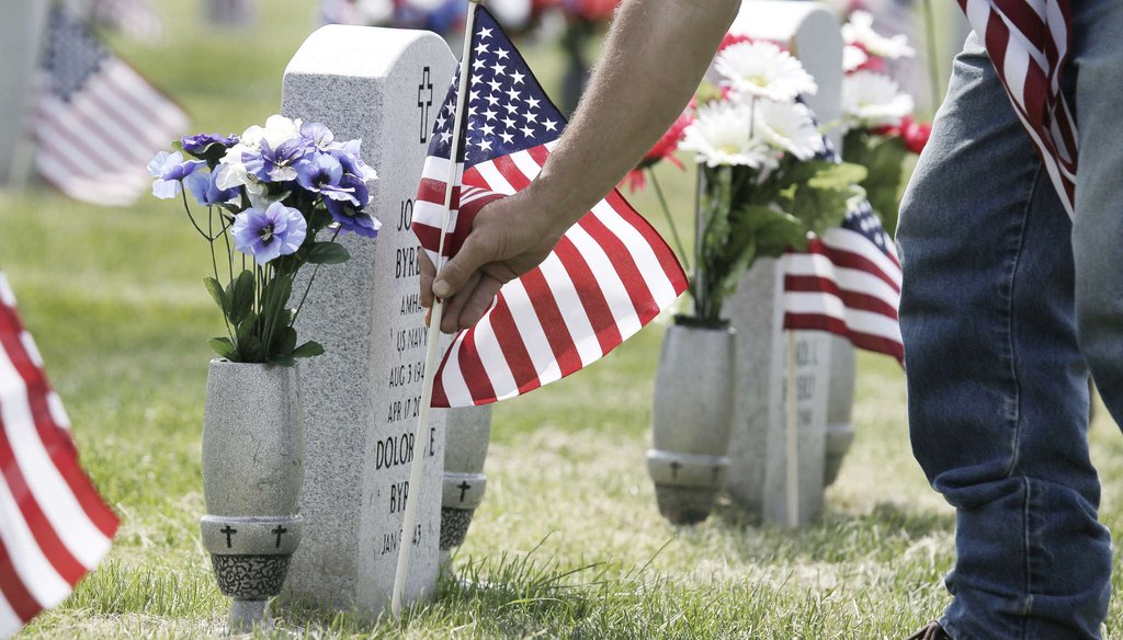 An employee at Gloucester County Veterans Memorial Cemetery in Monroe Township replaces a broken American flag on a veteran's grave. ELIZABETH ROBERTSON / Inquirer Staff Photographer