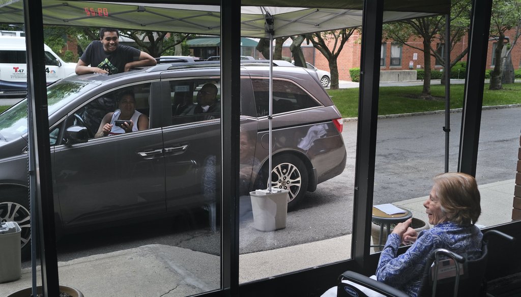 Gloria DeSoto, 92, right, visits with her family, in their car, from a window of the Hebrew Home at Riverdale, where she lives, in New York, Thursday, June 11, 2020. (AP)