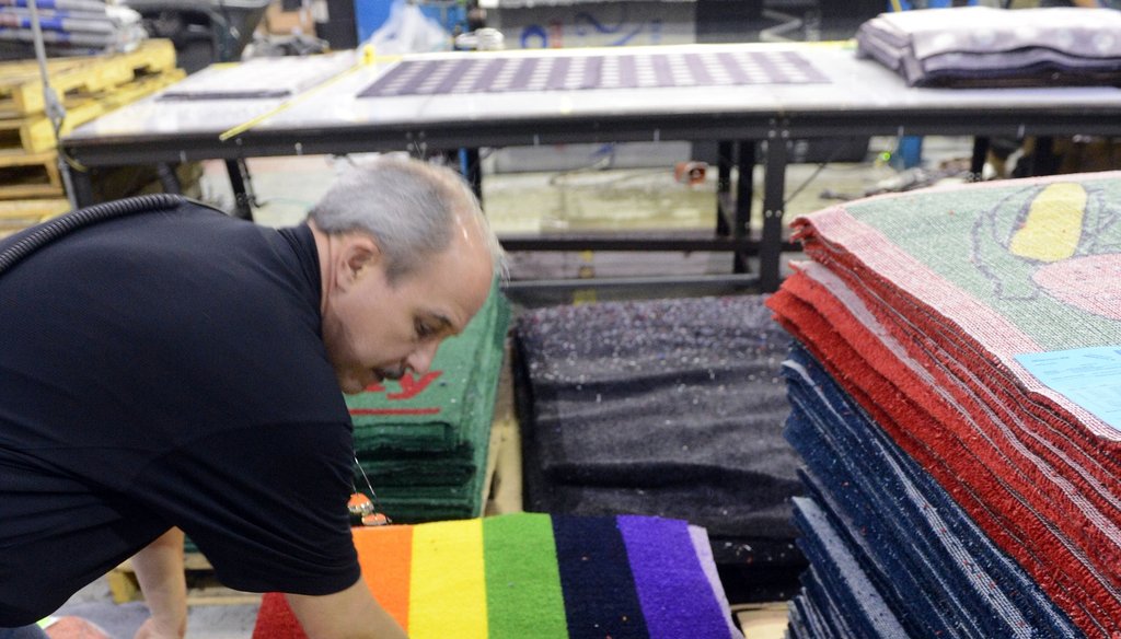 A production manager at Millennium Mats checks one of the printed products at its Suwanee plant in 2012, after the firm reversed its outsourcing efforts and shifted work back to the U.S. from China. Photo by Kent D. Johnson/ AJC.