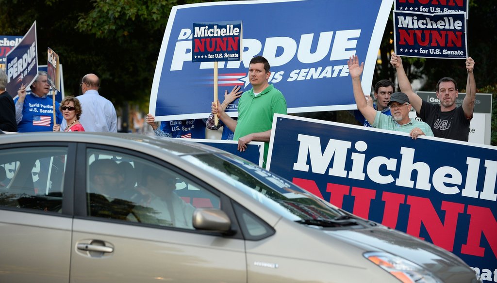 Supporters of U.S. Senate candidates Democrat Michelle Nunn and Republican David Perdue wave signs before before a debate in Atlanta on Oct. 26. David Tulis / AJC Special