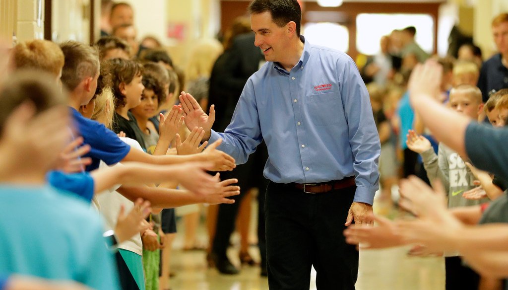 Gov. Scott Walker high-fived students after signing the 2017-'19 state budget bill into law. He touted an increase in state aid to schools, but previously he made cuts. (Dan Powers/USA TODAY NETWORK-Wisconsin)