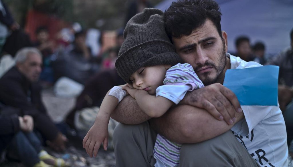 A Syrian refugee child sleeps in his father's arms while waiting at a resting point to board a bus in October 2015, after arriving on a dinghy from the Turkish coast to the northeastern Greek island of Lesbos. (Associated Press)