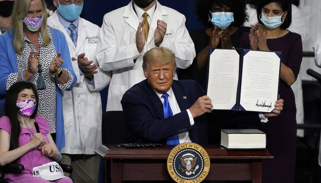 President Donald Trump holds up an executive order after delivering remarks on healthcare at Charlotte Douglas International Airport in Charlotte, N.C. (AP Photo/Chris Carlson)