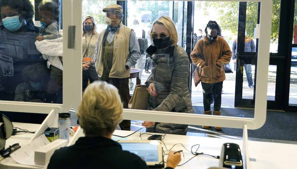 A masked election worker sits behind a clear barrier as she performs ID checks of potential voters on Election Day in Ridgeland, Miss., Tuesday, Nov. 3, 2020. (AP)