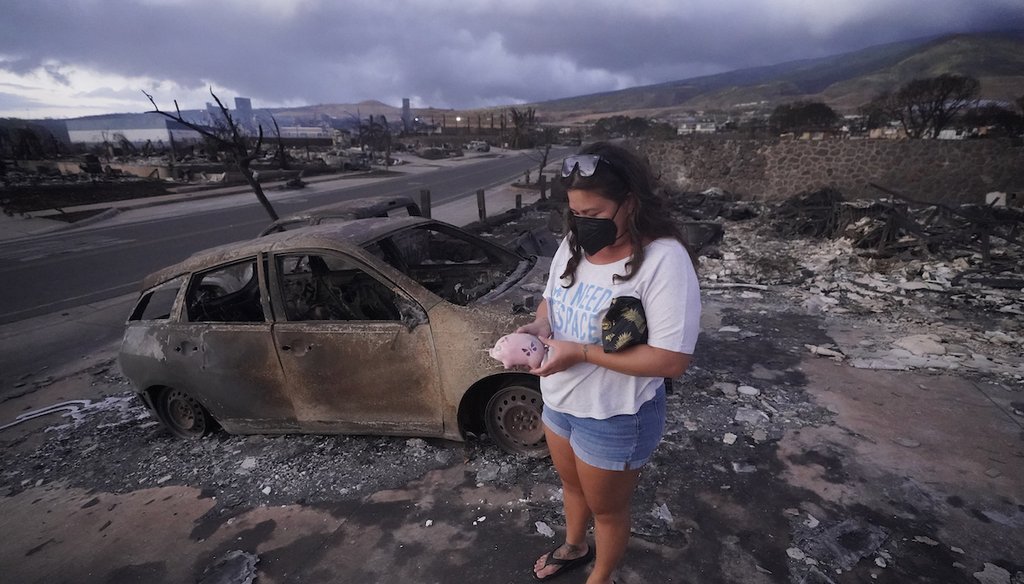 Summer Gerling picks up her piggy bank found in the rubble of her home following the wildfire Aug. 10, 2023, in Lahaina, Hawaii. (AP)