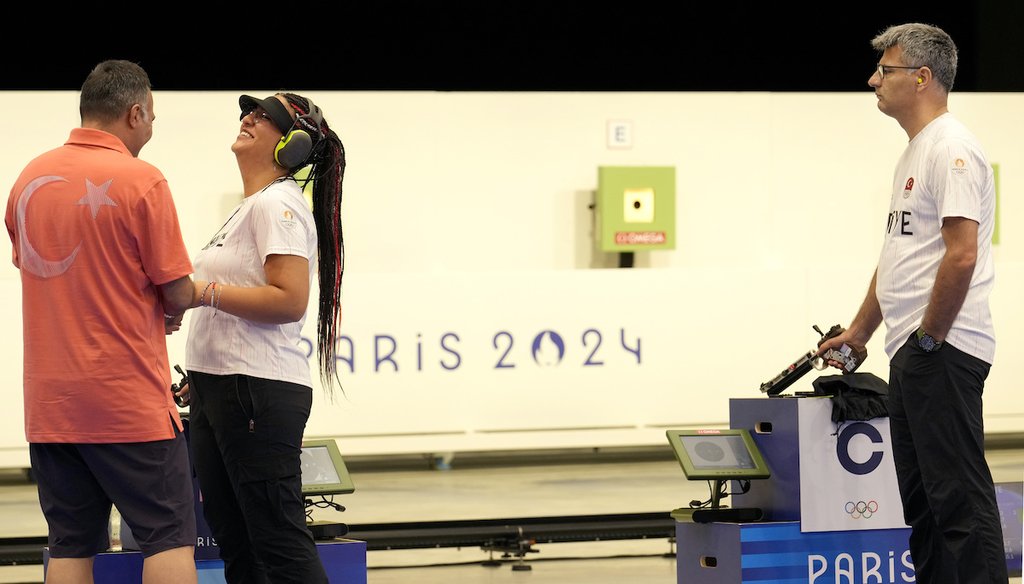 Turkish shooter Yusuf Dikec, right, looks on as his coach talks to Dikec's teammate Sevval Ilayda Tarhan, at the 10m air pistol mixed team final, in Chateauroux, France, at the 2024 Summer Olympics, July 30, 2024. (AP)